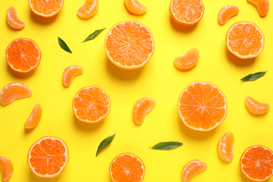 Photo of Flat lay composition with halves of fresh ripe tangerines and leaves on yellow background. Citrus fruit