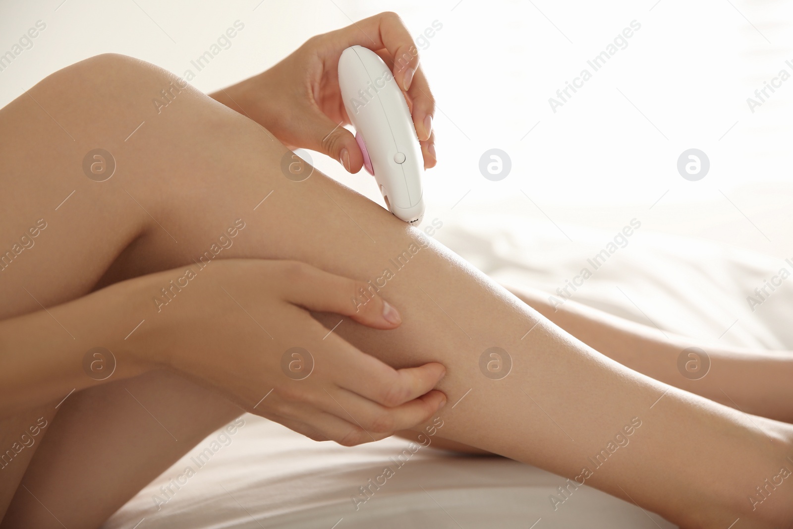Photo of Woman doing leg epilation procedure on bed, closeup