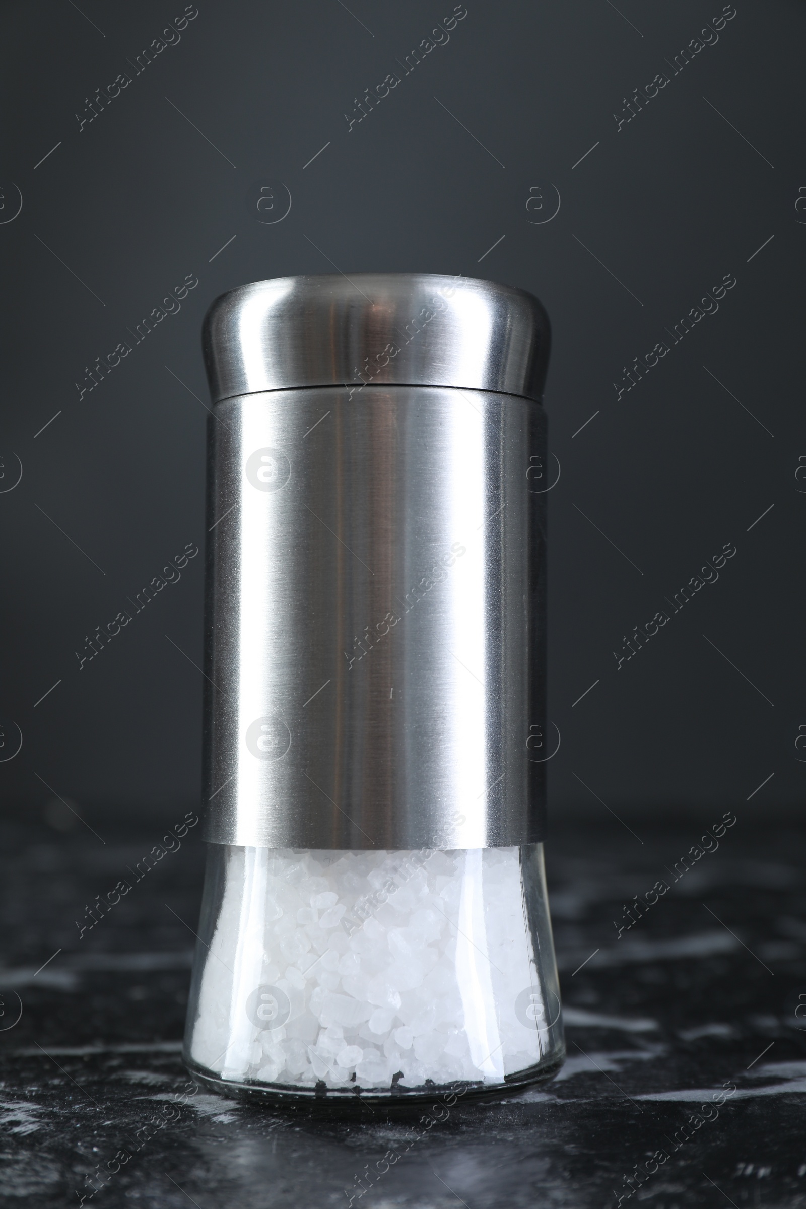 Photo of Salt shaker on dark marble table, closeup