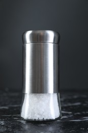 Salt shaker on dark marble table, closeup