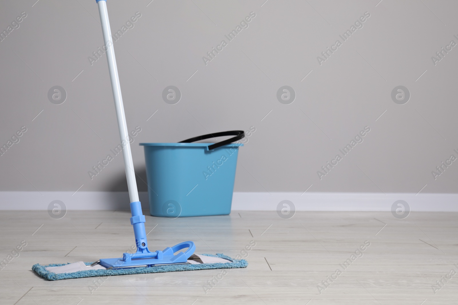 Photo of Mop and plastic bucket indoors. Space for text