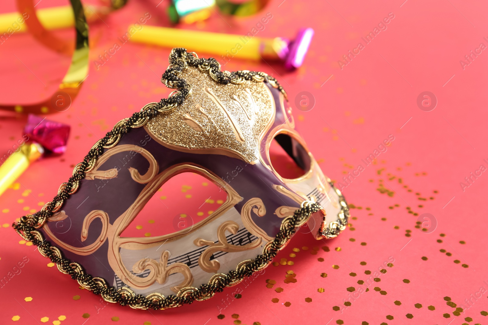 Photo of Beautiful carnival mask with party decor on coral background, closeup