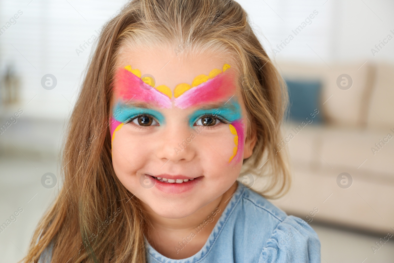 Photo of Cute little girl with face painting indoors