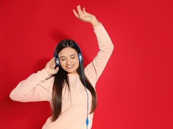 Photo of Attractive young woman enjoying music in headphones on color background. Space for text