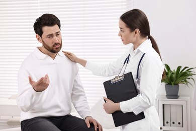 Photo of Doctor with clipboard consulting patient during appointment in clinic