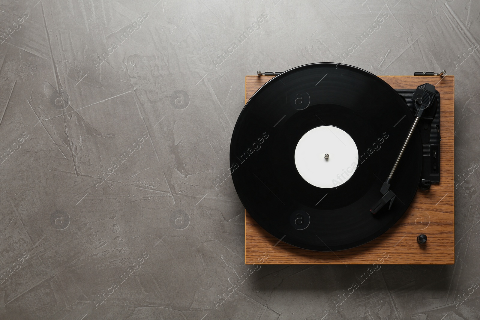 Photo of Turntable with vinyl record on grey background, top view. Space for text