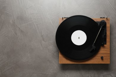 Photo of Turntable with vinyl record on grey background, top view. Space for text