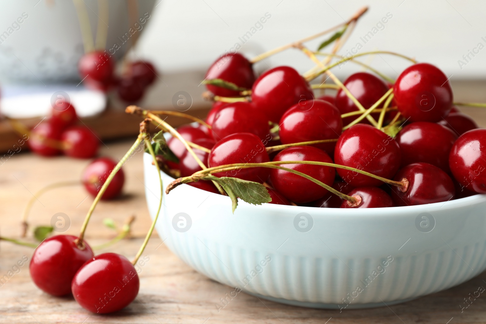Photo of Bowl of delicious cherries on wooden table, closeup view. Space for text