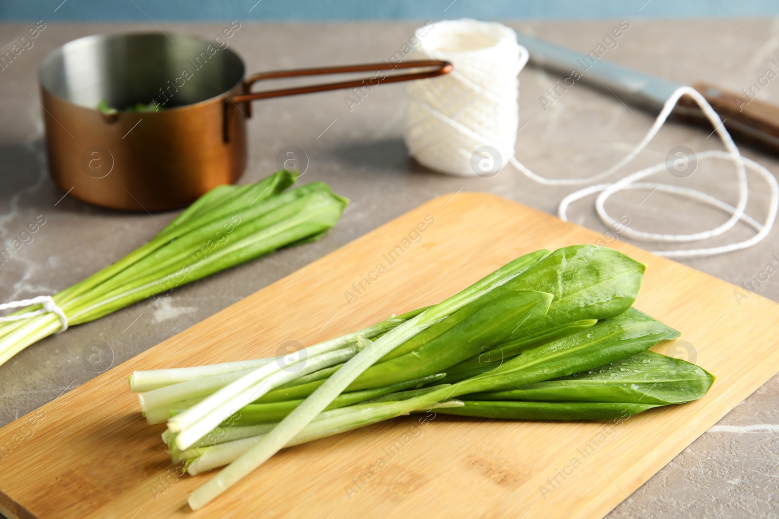 Photo of Board with wild garlic or ramson on grey table, closeup