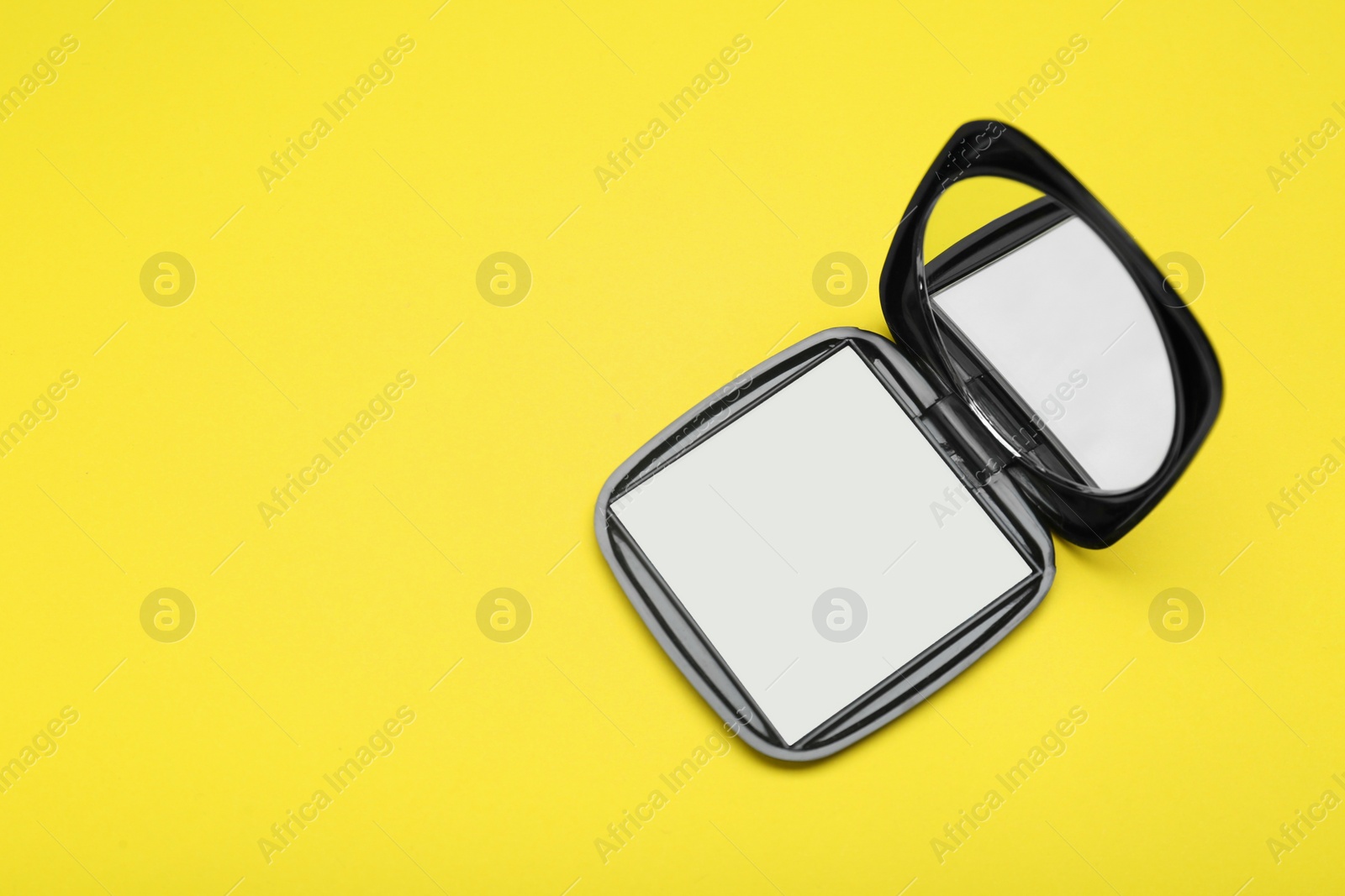 Photo of Stylish cosmetic pocket mirror on yellow background, top view. Space for text