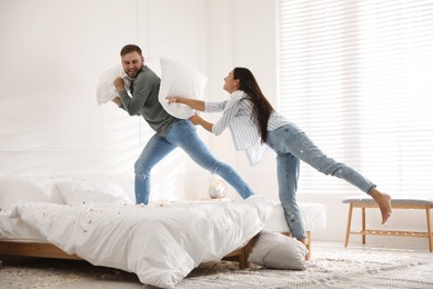 Happy young couple having fun pillow fight in bedroom