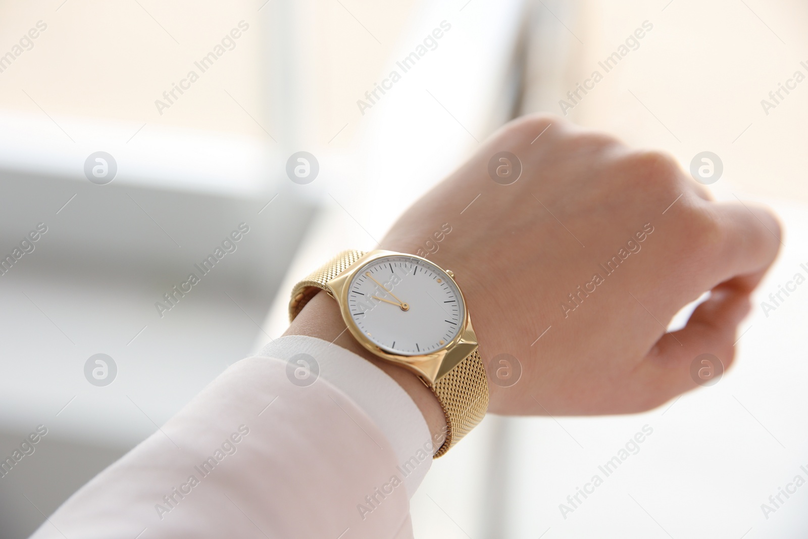 Photo of Woman with luxury wristwatch on blurred background, closeup