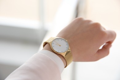 Woman with luxury wristwatch on blurred background, closeup