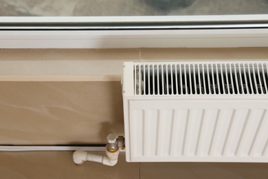 Photo of Modern heating radiator in room against window