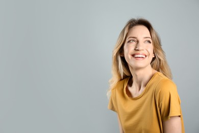 Photo of Portrait of happy young woman with beautiful blonde hair and charming smile on grey background. Space for text
