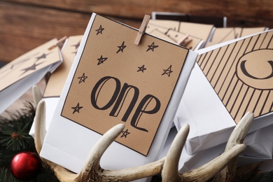 Photo of Paper bags and festive decor on wooden background, closeup. Christmas advent calendar