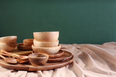 Photo of Set of wooden dishware and utensils on table against green background. Space for text