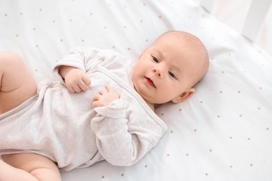 Cute little baby lying in crib at home, top view