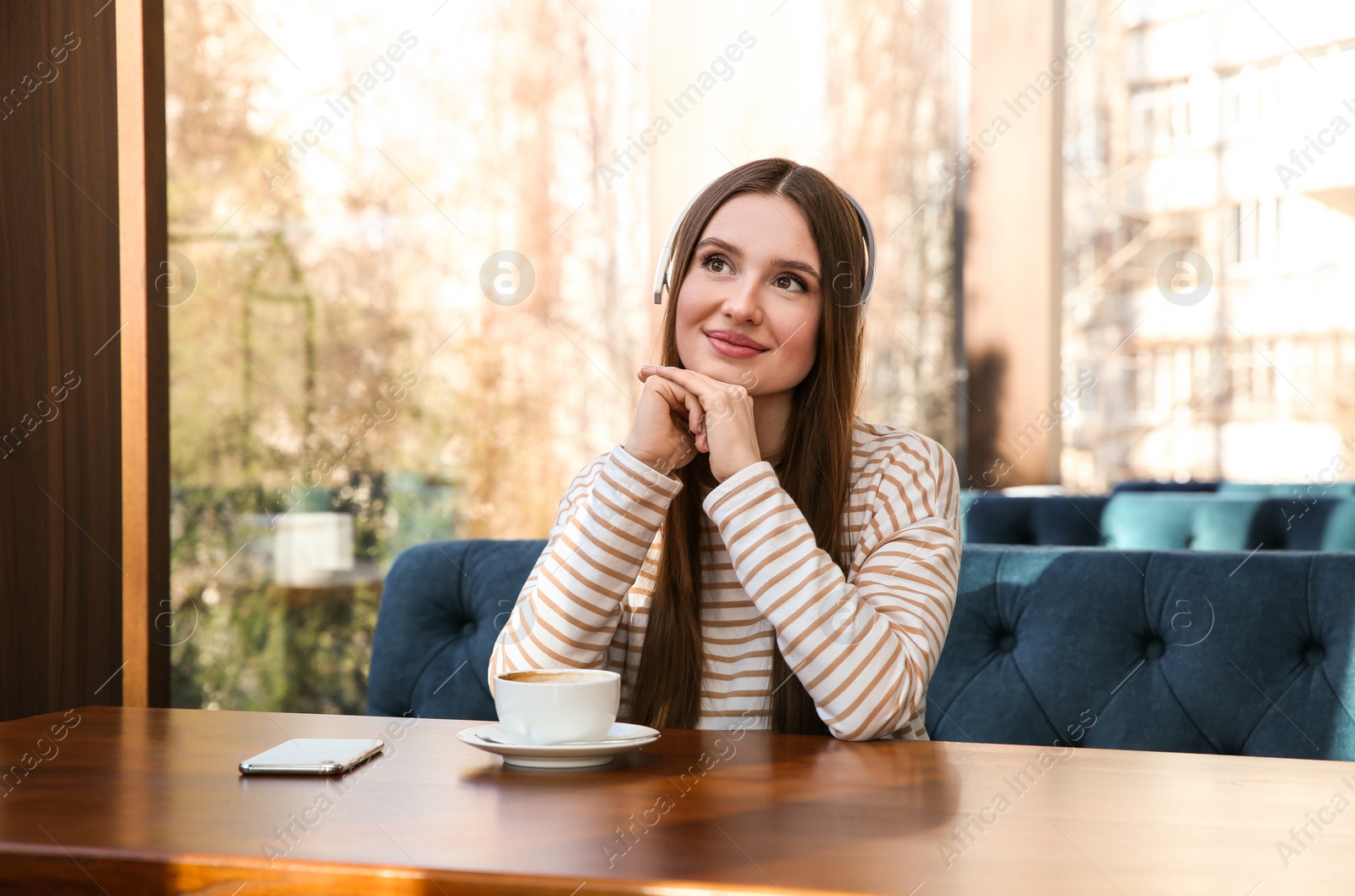 Photo of Woman listening to audiobook at table in cafe