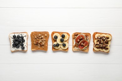 Different sweet delicious toasts on white wooden table, flat lay