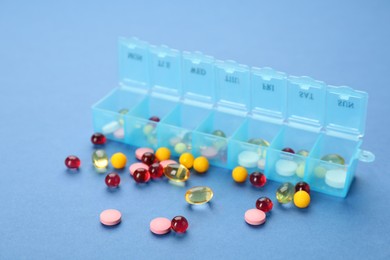 Photo of Plastic box with different pills on light blue background