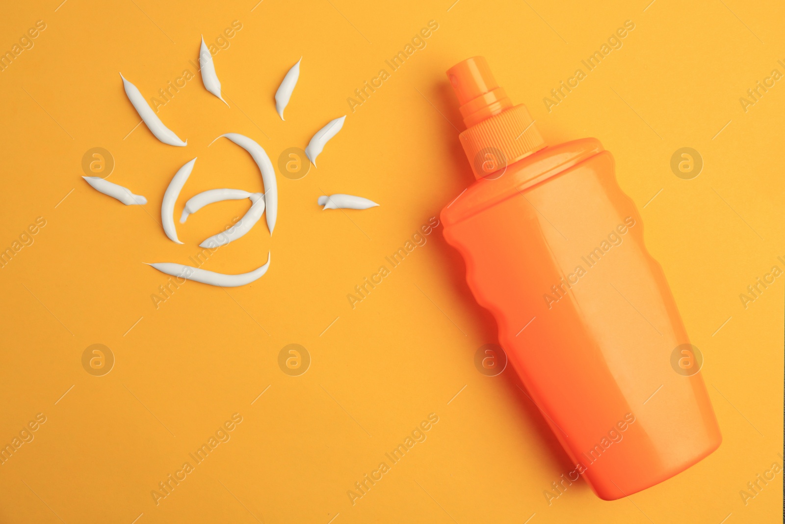 Photo of Drawing of sun and bottle with sunscreen on orange background, top view. Skin protection