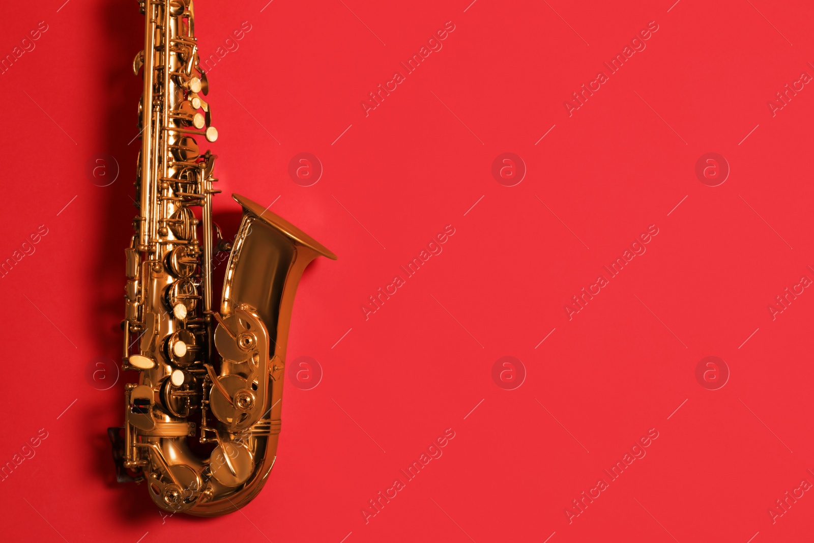 Photo of Beautiful saxophone on red background, top view. Space for text
