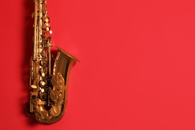 Beautiful saxophone on red background, top view. Space for text