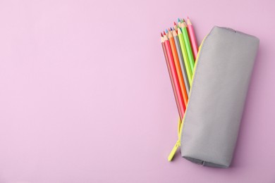 Photo of Many colorful pencils in pencil case on pink background, top view. Space for text