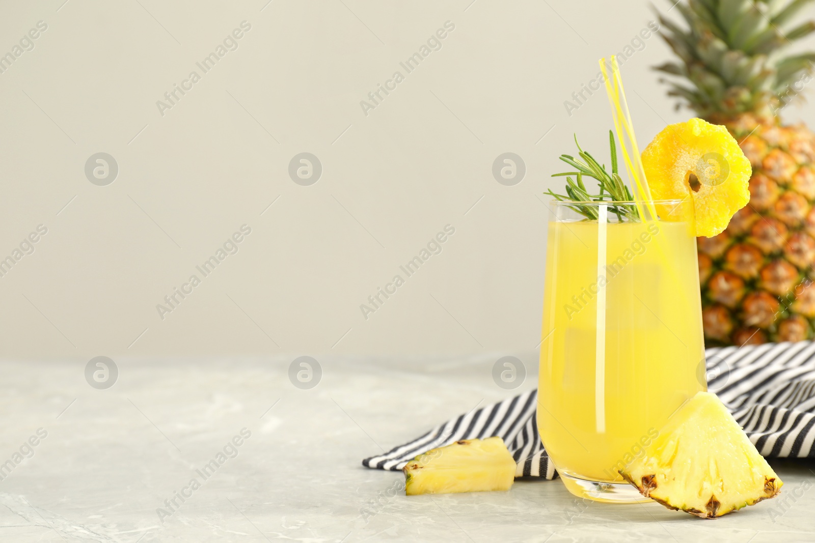 Photo of Tasty pineapple cocktail with rosemary and sliced fruit on light grey marble table. Space for text
