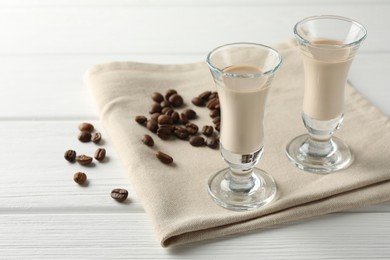 Coffee cream liqueur in glasses and beans on white wooden table