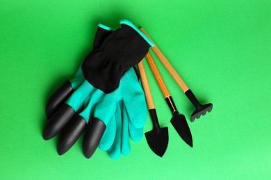 Photo of Gardening gloves and tools on green background, flat lay