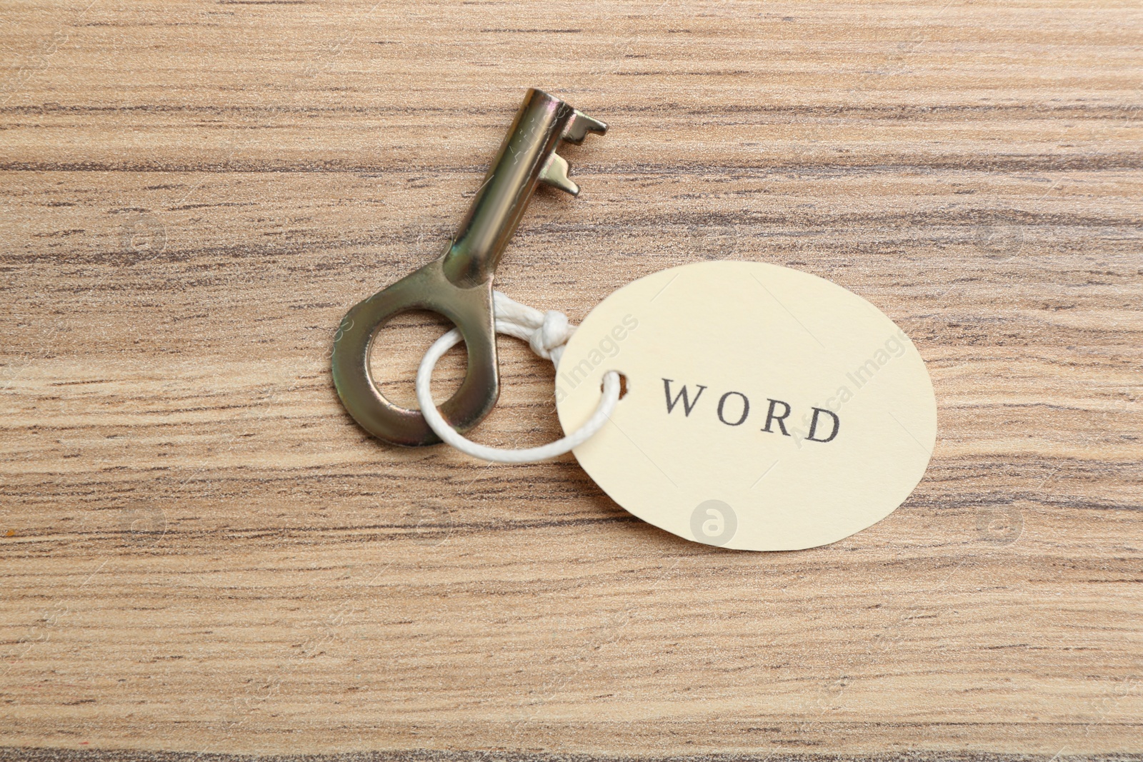 Photo of Vintage key with tag on wooden table, top view. Keyword concept