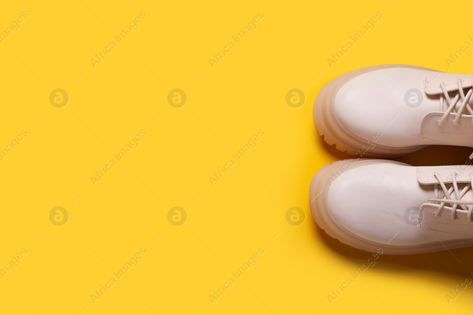 Photo of Pair of stylish leather shoes on yellow background, flat lay. Space for text