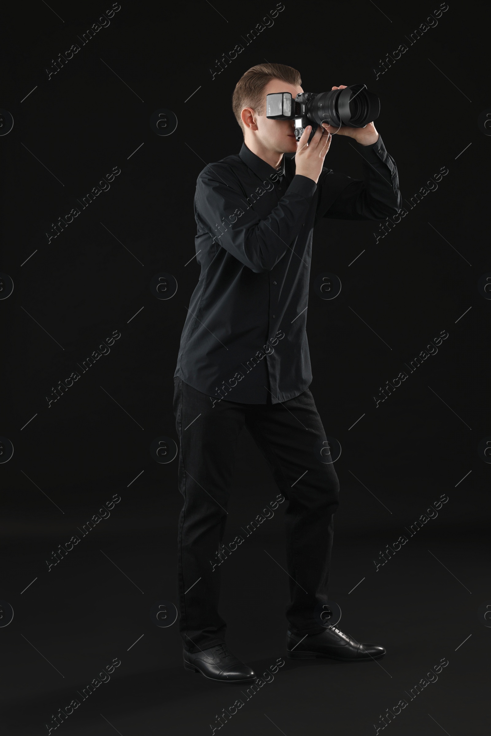 Photo of Professional photographer taking picture on black background