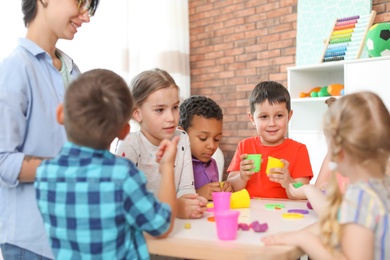 Photo of Young woman playing with little children indoors