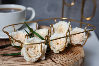 Photo of Decorative gold holder with flowers and cup of coffee, closeup. Interior design