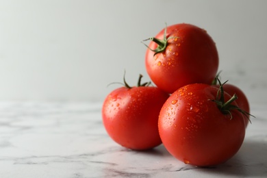 Photo of Fresh ripe tomatoes on white marble table, closeup. Space for text