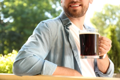 Young man with cold kvass outdoors, closeup. Traditional Russian summer drink