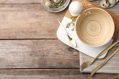 Photo of Rustic Easter table setting with eggs and floral decor, flat lay. Space for text