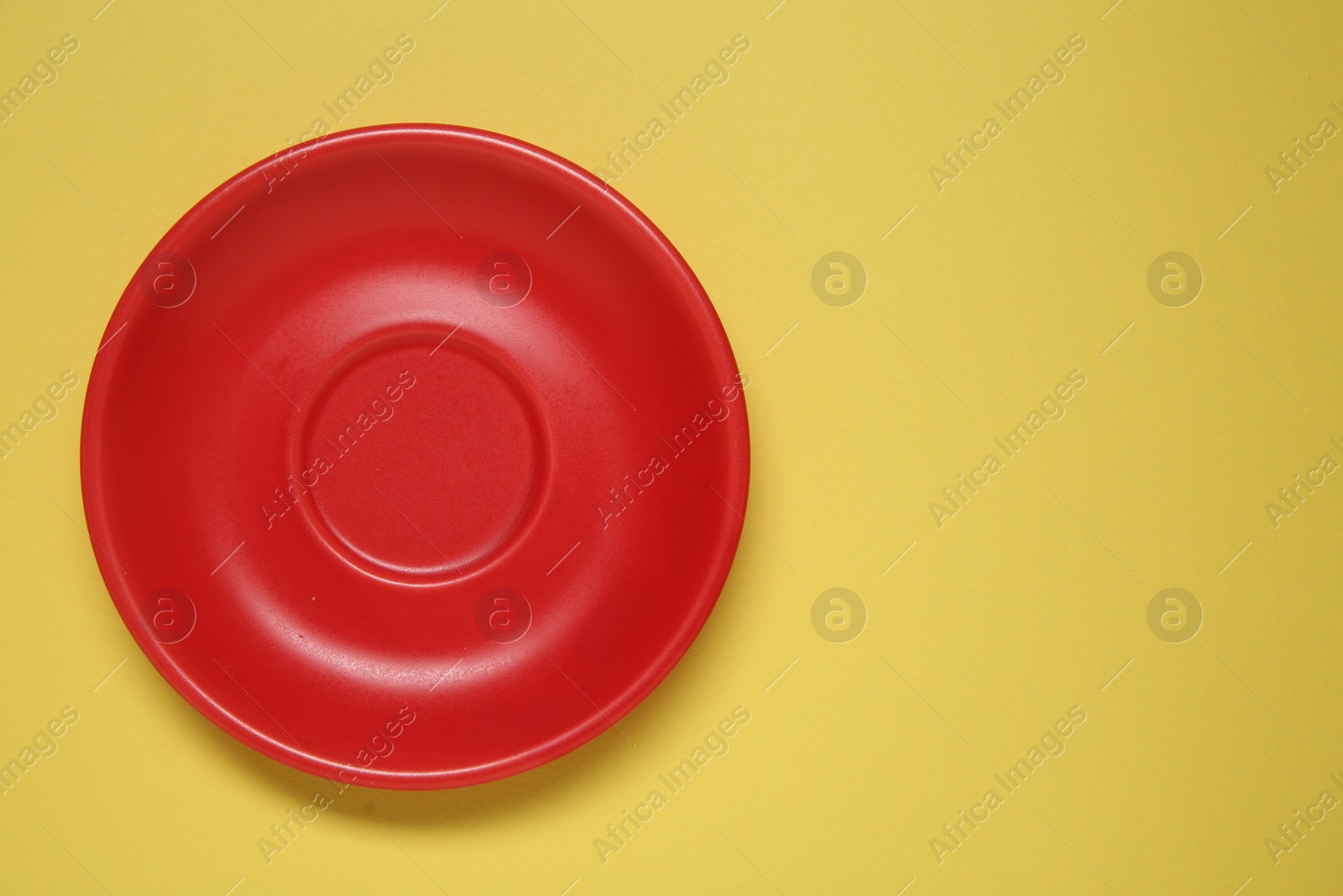 Photo of One red ceramic plate on yellow background, top view. Space for text