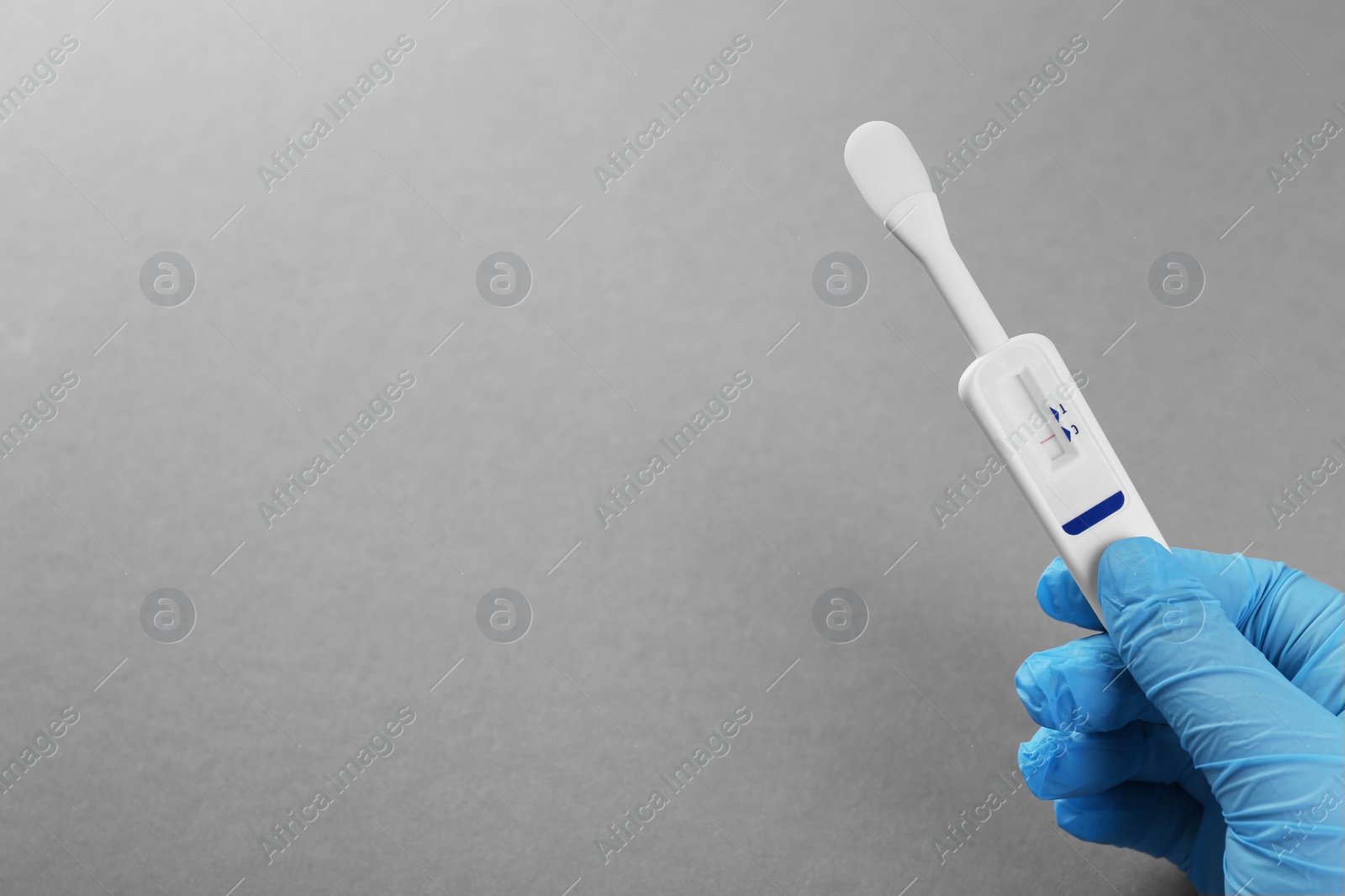 Photo of Doctor holding disposable express test on light grey background, closeup. Space for text