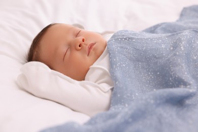 Photo of Cute newborn baby sleeping under blue blanket on bed, closeup