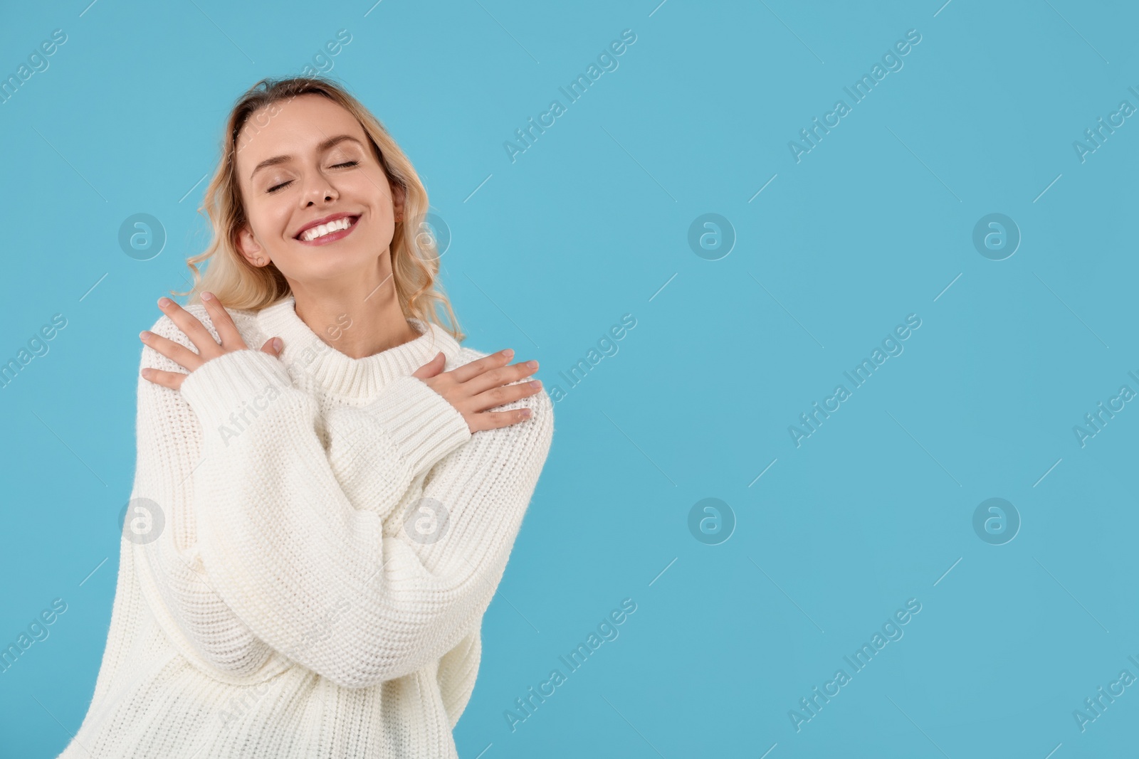 Photo of Happy woman in stylish warm sweater on light blue background. Space for text