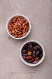 Photo of Bowls with different types of beans on light grey table, flat lay