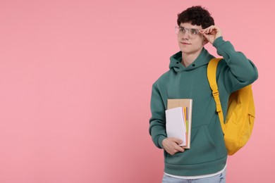 Portrait of student with backpack and notebooks on pink background. Space for text