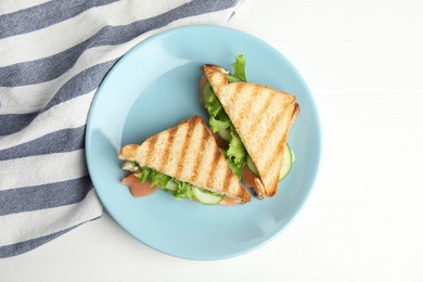 Blue plate with tasty sandwiches on white table, top view