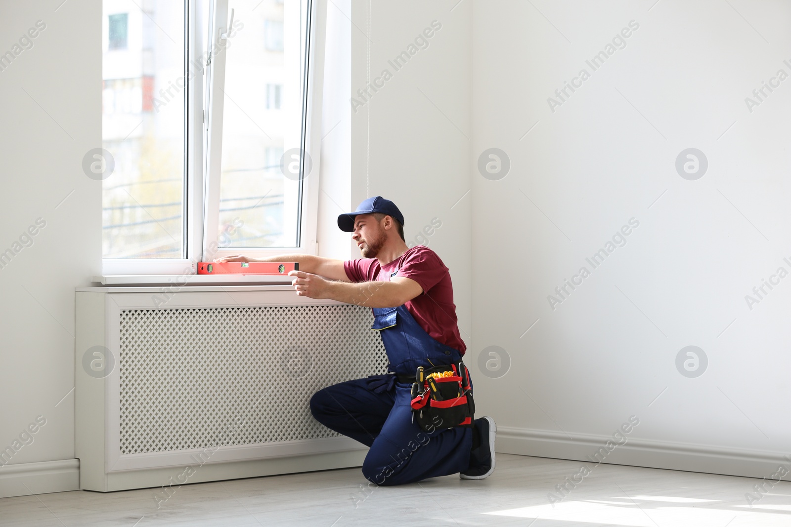 Photo of Handyman in uniform working with building level indoors. Professional construction tools