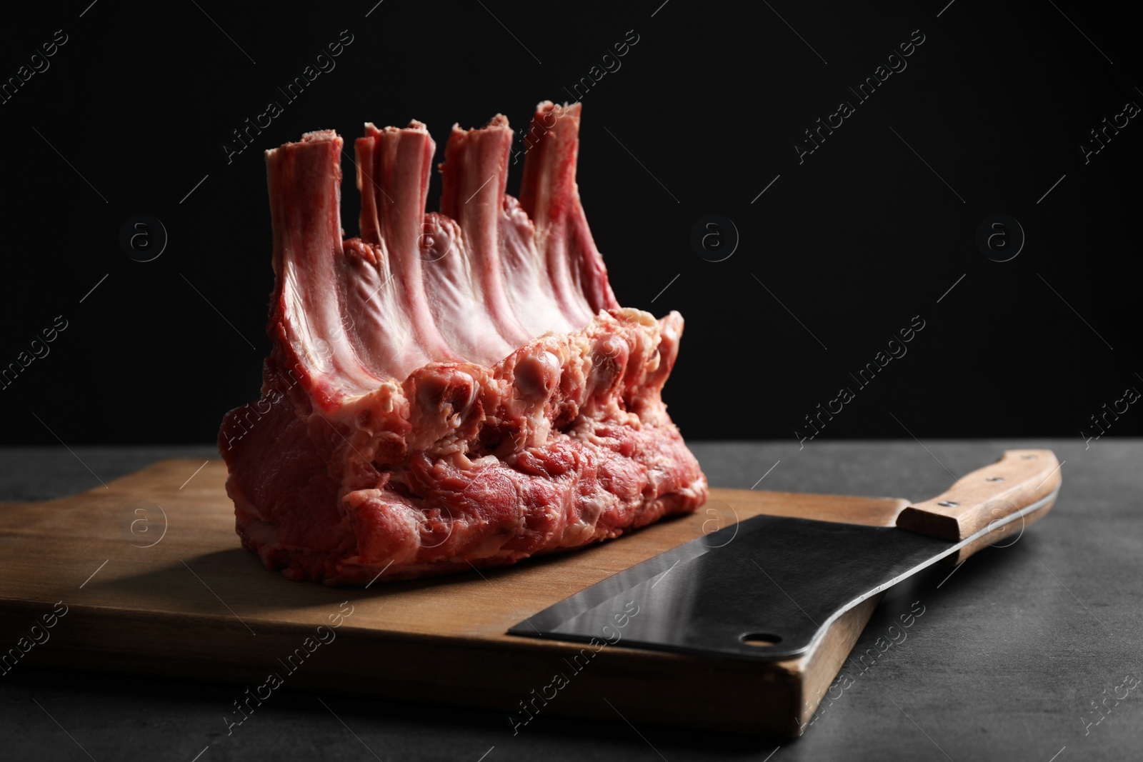 Photo of Raw ribs on grey table against black background