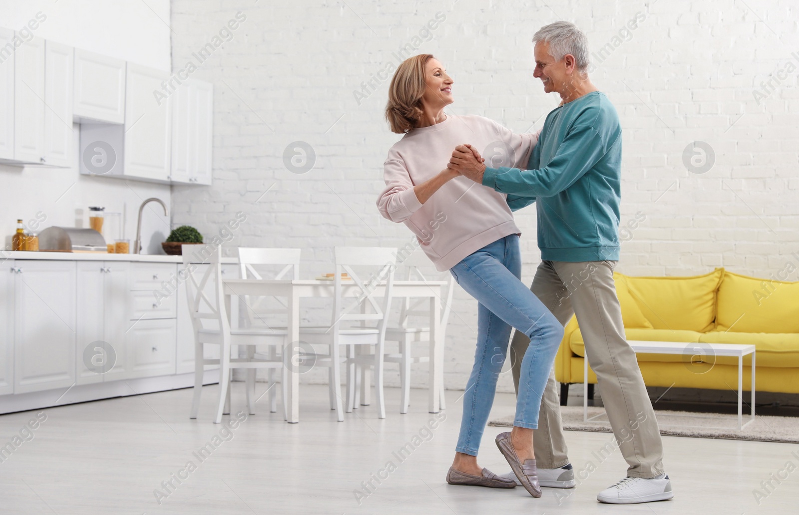 Photo of Happy senior couple dancing together in kitchen